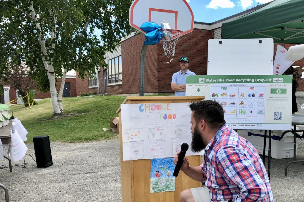 Person kneeling in front of podium, Waterville event